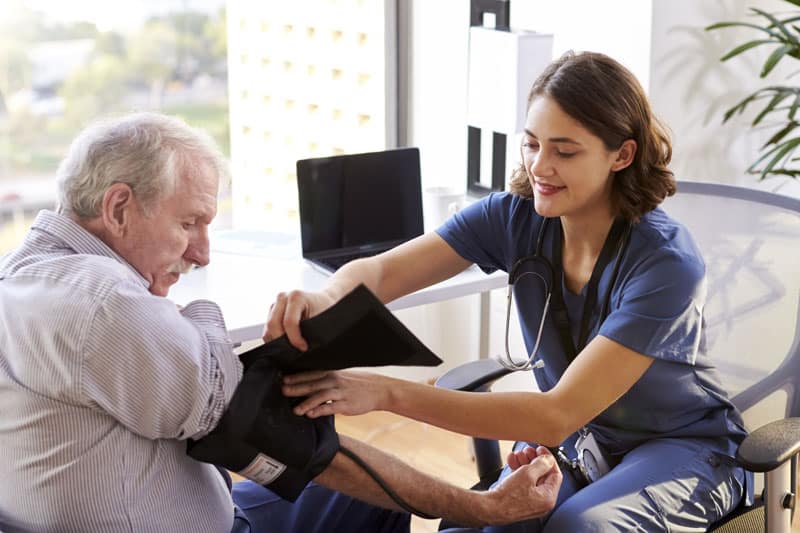 Senior with nurse having blood pressure checked