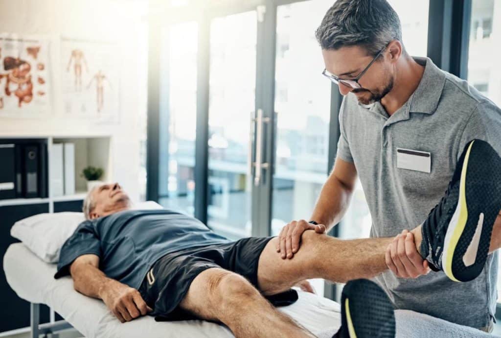 Physiotherapist treating an elderly patient who has arthritis.