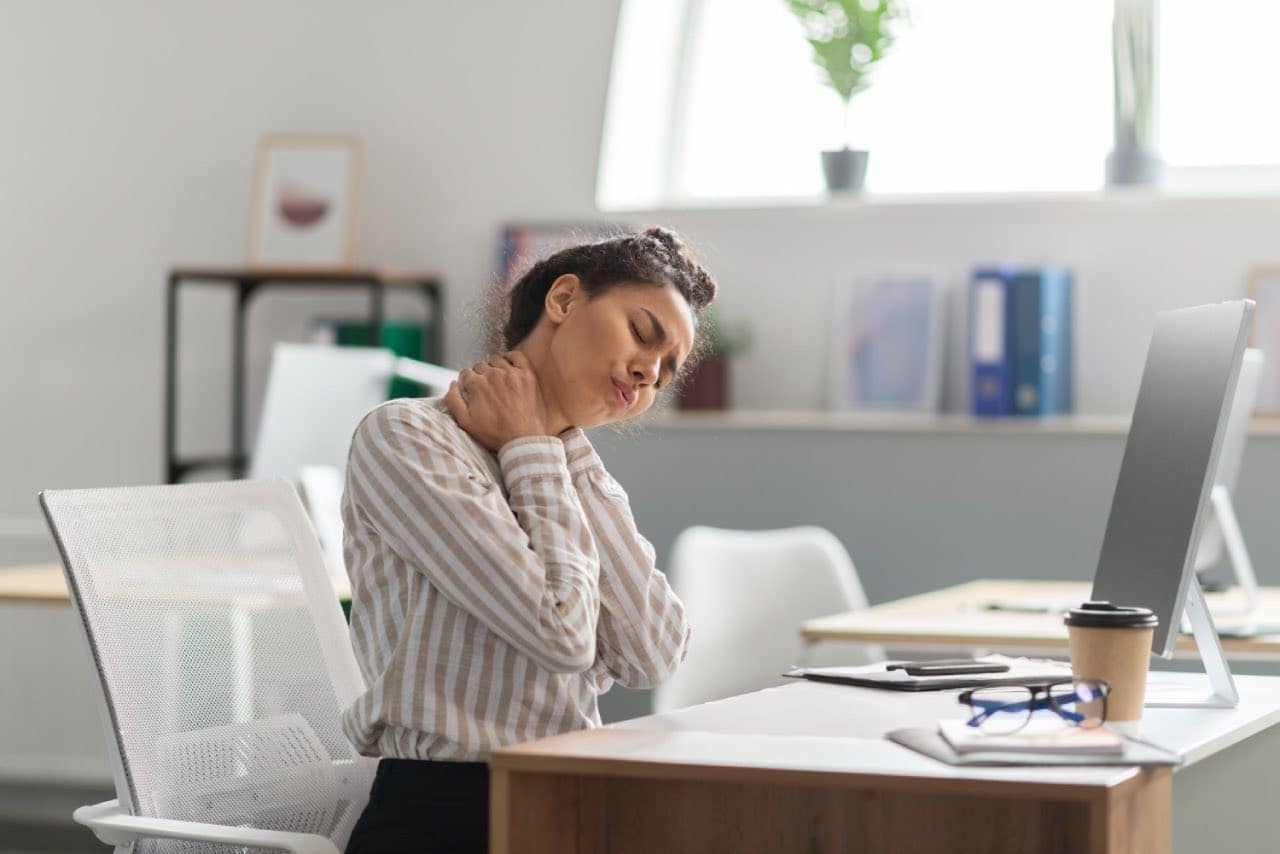 A young woman working on screen suffering neck pain