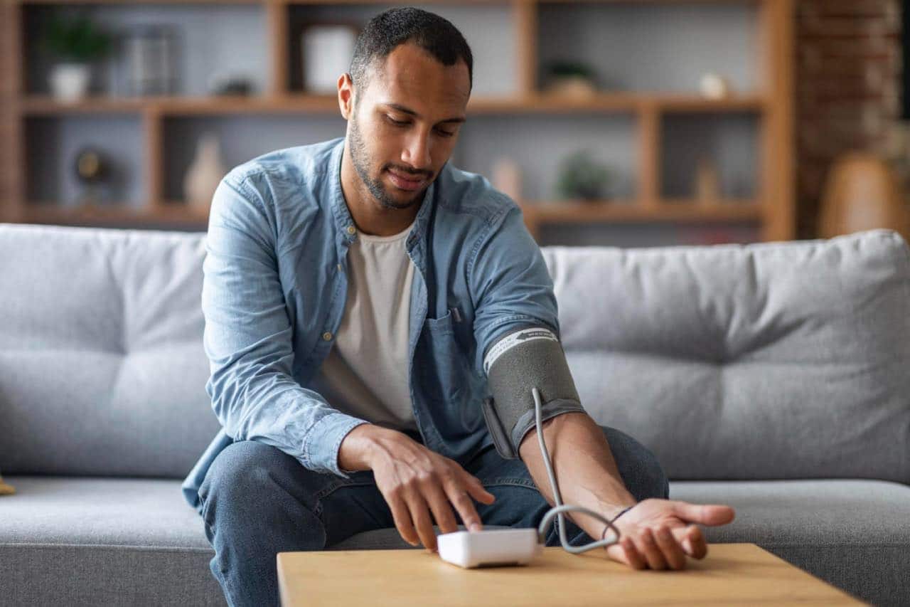 Young man using blood pressure device to self-check