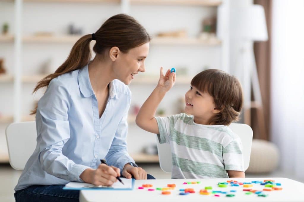 Young boy practising O sound with speech pathologist in speech therapy