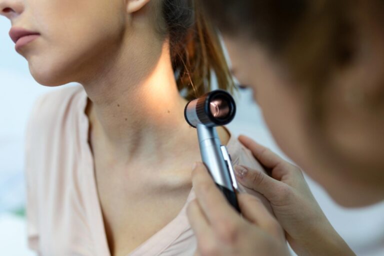 Skin doctor performing skin cancer check on a young woman's neck.