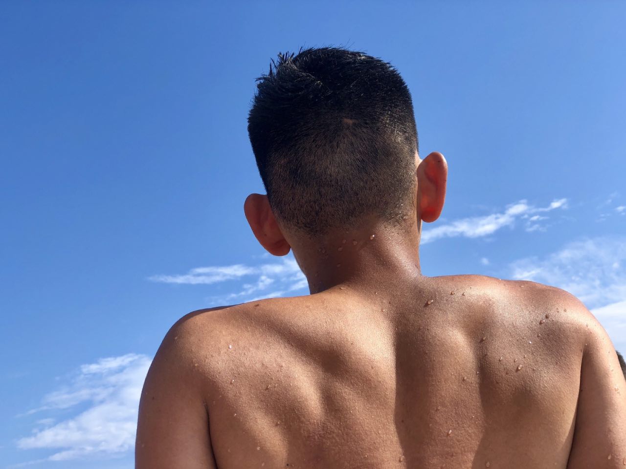 A young asian man sitting under the sun for skin tanning damaging the skin by UV rays