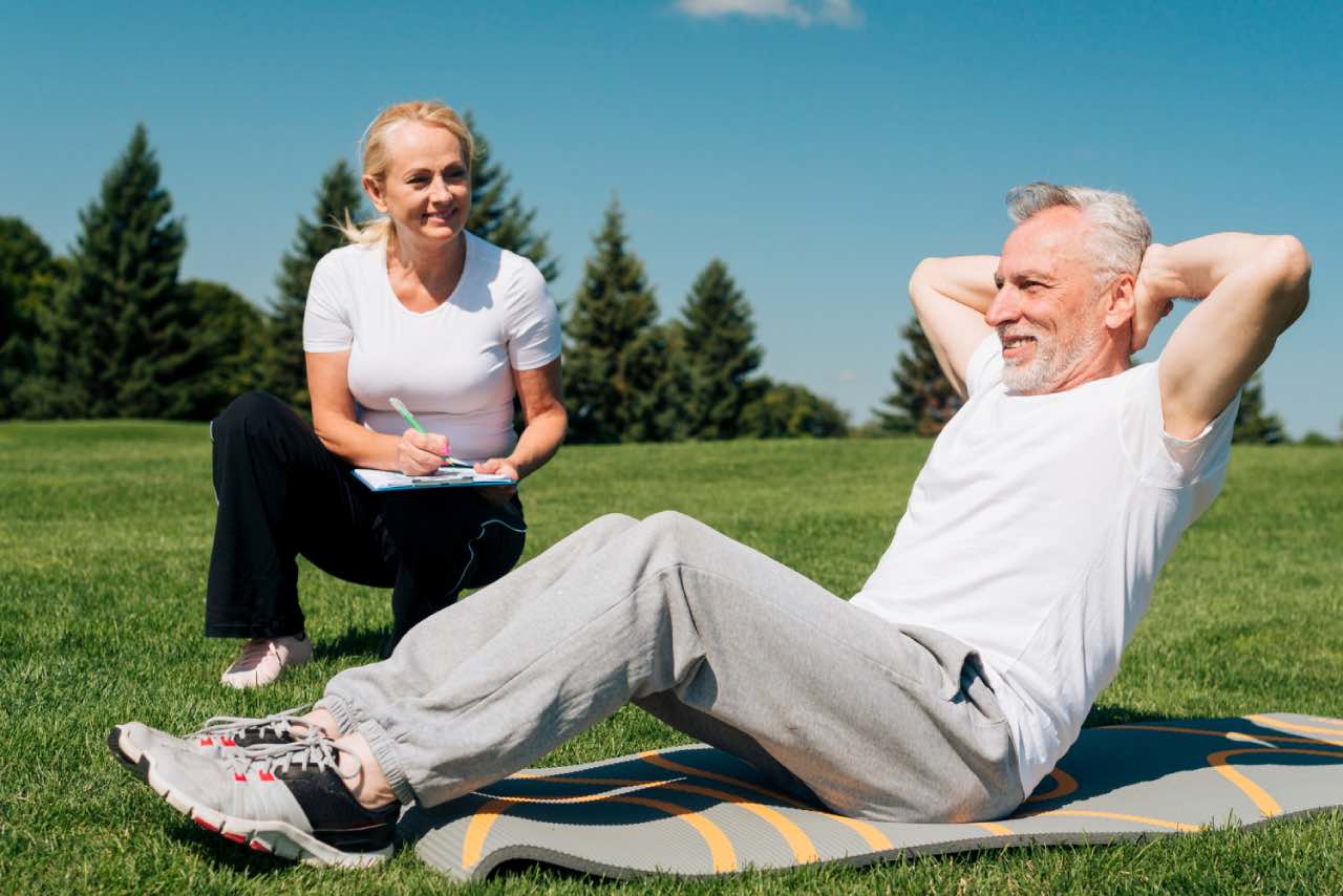A senior man is exercising to improve mental wellbeing, with help of the exercise physiologist.